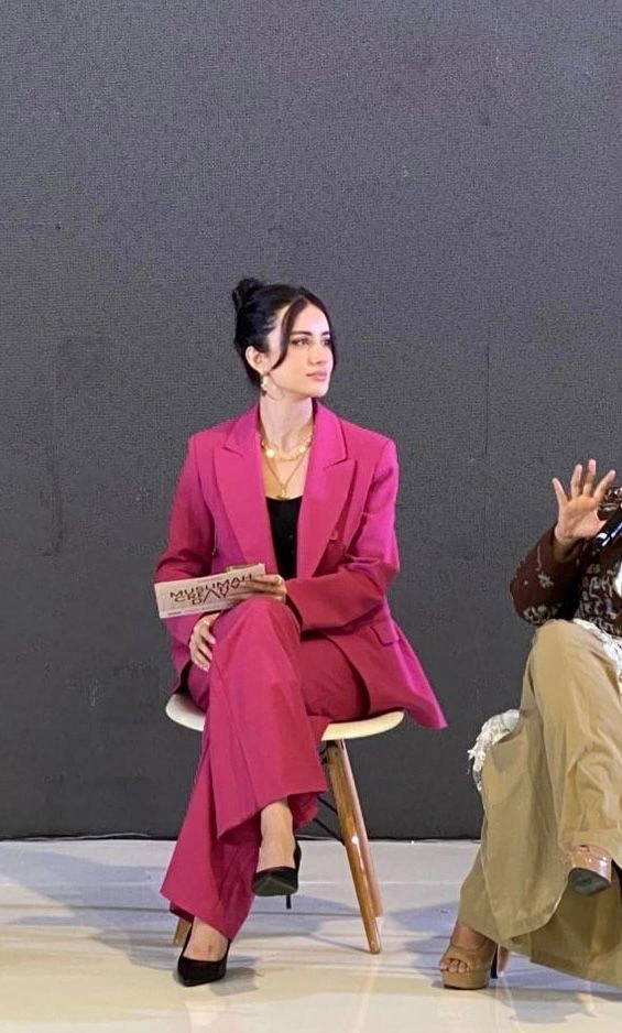 Portrait of a panelist in a pink suit seated on stage at Muslimah Creative Day